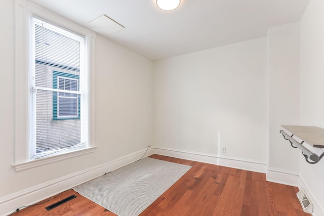 unfurnished room featuring a wealth of natural light, visible vents, and wood finished floors