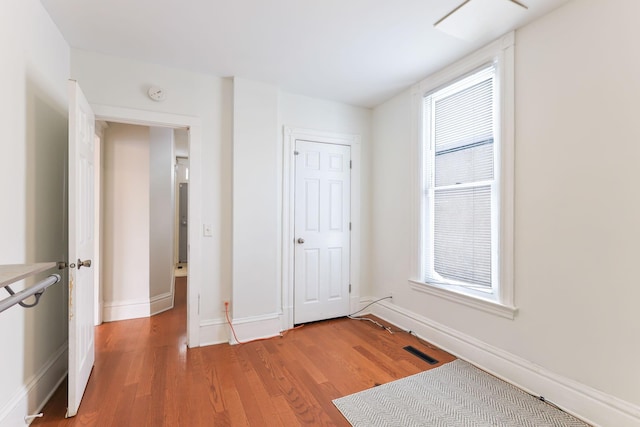 unfurnished bedroom featuring visible vents, multiple windows, light wood-type flooring, and baseboards