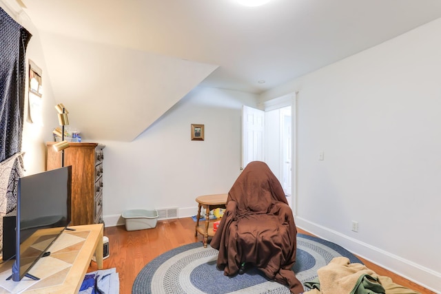 living area featuring wood finished floors, visible vents, and baseboards