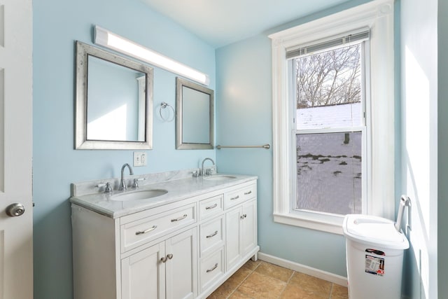 bathroom featuring double vanity, baseboards, and a sink