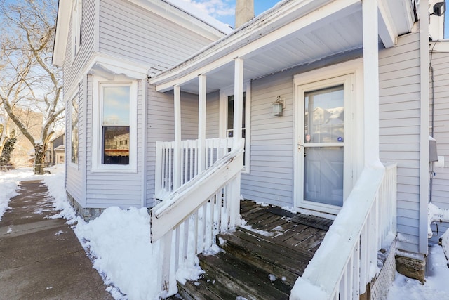 snow covered property entrance with covered porch