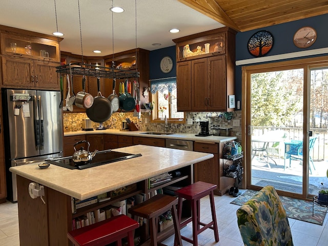 kitchen with black electric stovetop, a sink, light countertops, freestanding refrigerator, and open shelves