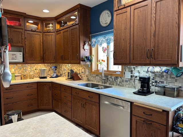 kitchen featuring white microwave, a sink, light countertops, dishwasher, and glass insert cabinets