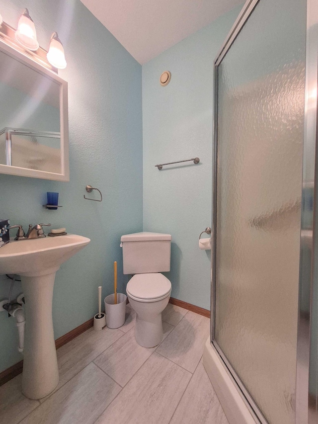 15633 Explorer Ln, Park Rapids, MN 56470 - full bathroom featuring a stall shower, toilet, baseboards, and a sink