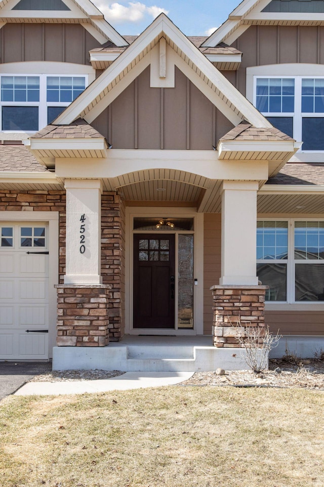 doorway to property with a shingled roof, board and batten siding, and stone siding