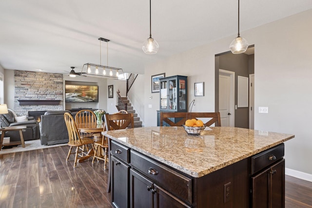 kitchen with pendant lighting, a fireplace, a ceiling fan, and dark wood-style floors