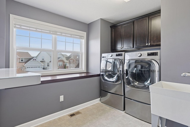washroom featuring independent washer and dryer, visible vents, cabinet space, a sink, and baseboards