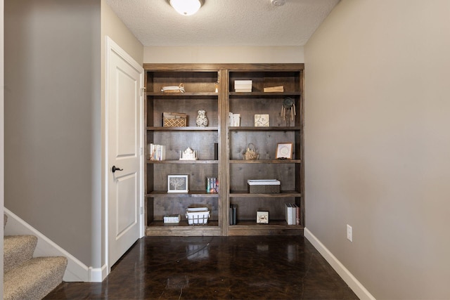 interior space with a textured ceiling and baseboards