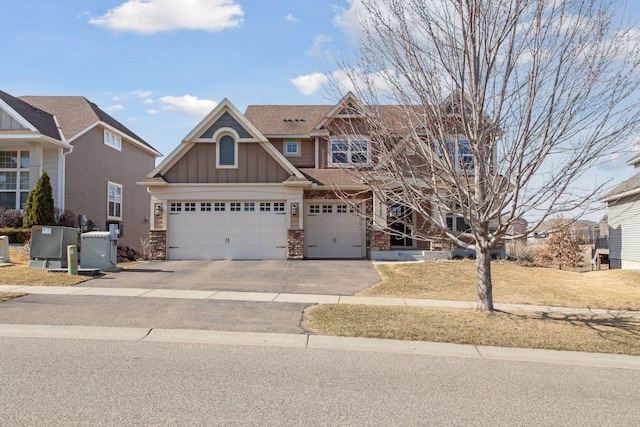 craftsman-style home with an attached garage, aphalt driveway, board and batten siding, and stone siding