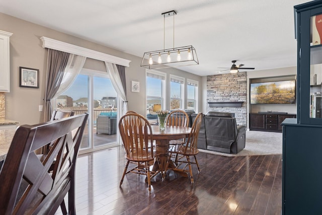 dining space with a ceiling fan, dark wood finished floors, plenty of natural light, and a fireplace