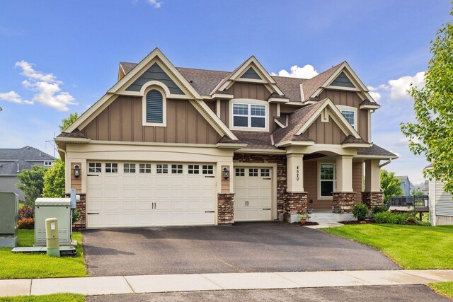 4520 Bailey Lake Dr, Woodbury, MN 55129 - craftsman-style house with board and batten siding, asphalt driveway, stone siding, roof with shingles, and a front lawn