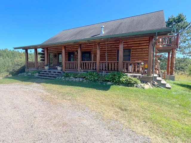 log cabin featuring covered porch, log exterior, a front lawn, and roof with shingles