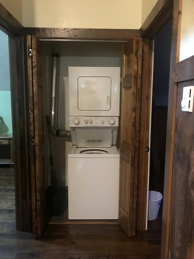 laundry area featuring stacked washer and dryer, laundry area, and dark wood-style flooring