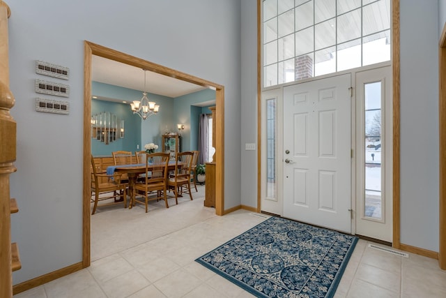 entrance foyer with visible vents, baseboards, a high ceiling, and an inviting chandelier