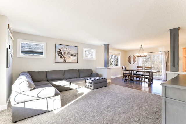 living area featuring baseboards, a textured ceiling, an inviting chandelier, and dark colored carpet