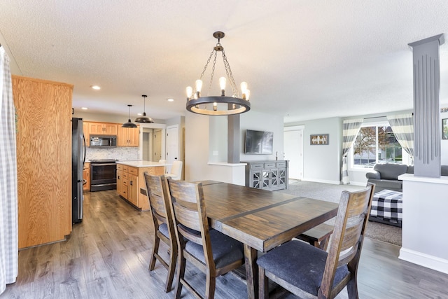 dining area with a notable chandelier, a textured ceiling, wood finished floors, recessed lighting, and baseboards