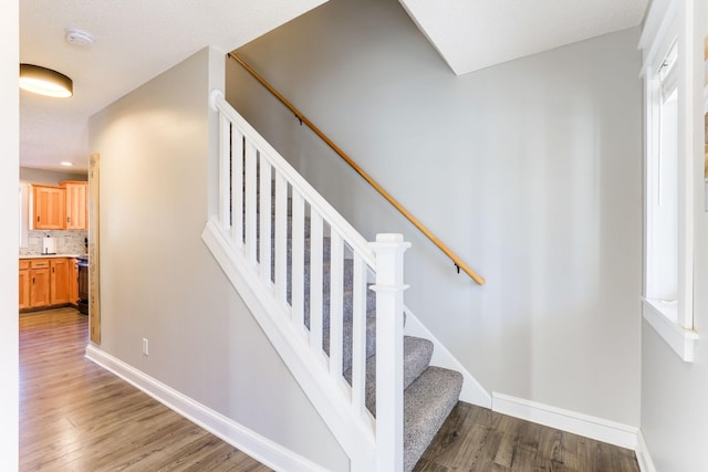 stairs with wood finished floors and baseboards