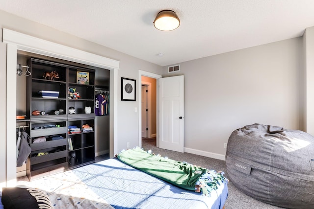 carpeted bedroom with baseboards, visible vents, and a closet