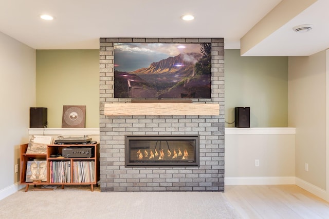 living area featuring recessed lighting, a fireplace, baseboards, and wood finished floors