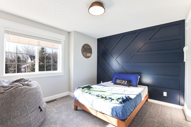 bedroom featuring visible vents, a textured ceiling, carpet, and baseboards