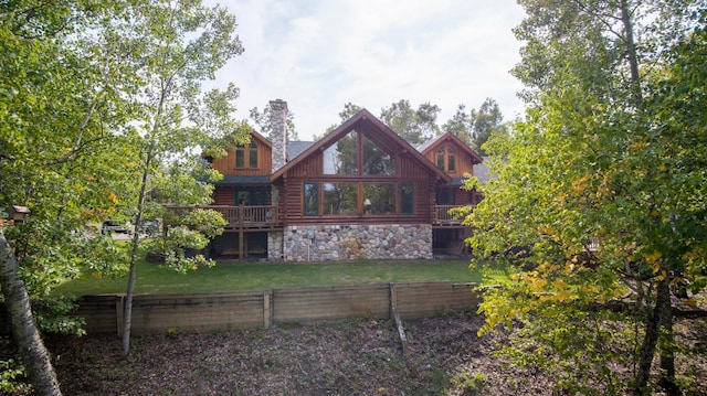 rear view of house featuring a yard, a chimney, fence, log siding, and stone siding