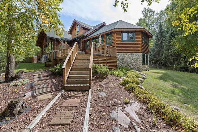 cabin with stairs, stone siding, a front lawn, and a wooden deck