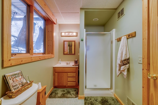 full bath featuring visible vents, toilet, vanity, a paneled ceiling, and a shower stall