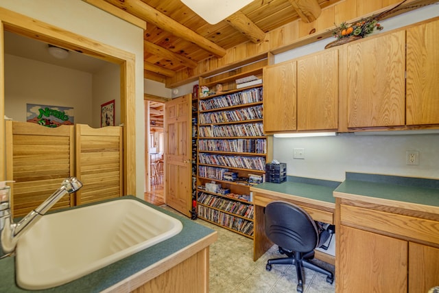 home office with beam ceiling, built in desk, light floors, wood ceiling, and a sink