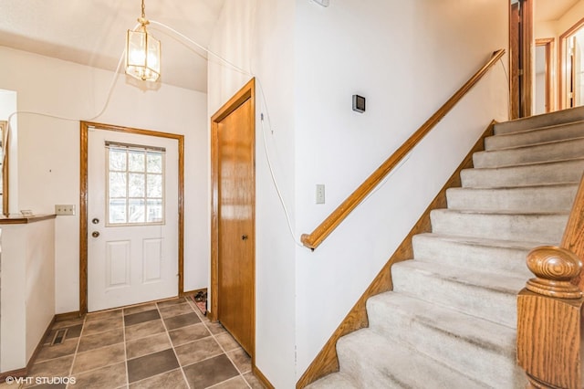 foyer featuring dark tile patterned floors and stairs