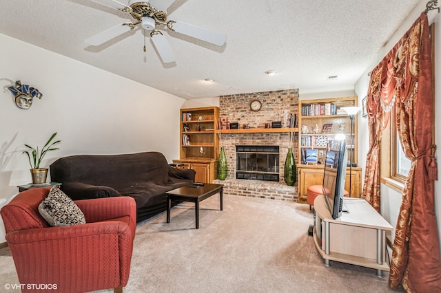 carpeted living area featuring ceiling fan, built in features, a fireplace, and a textured ceiling