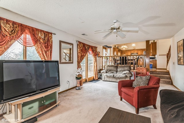 living room with stairway, visible vents, ceiling fan, a textured ceiling, and light carpet