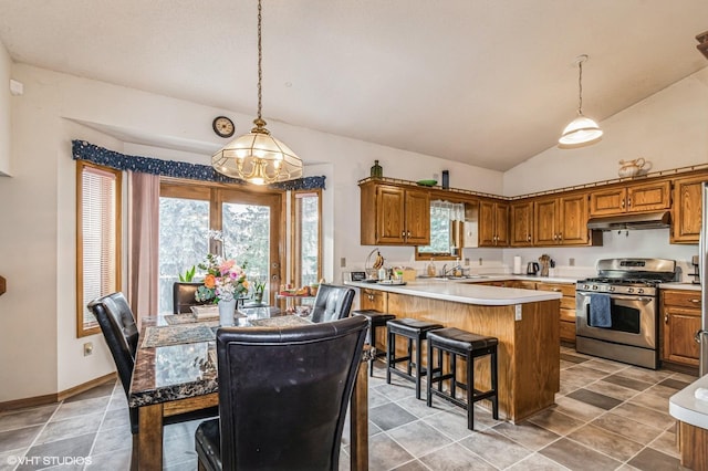 kitchen with light countertops, stainless steel range with gas stovetop, brown cabinets, and under cabinet range hood