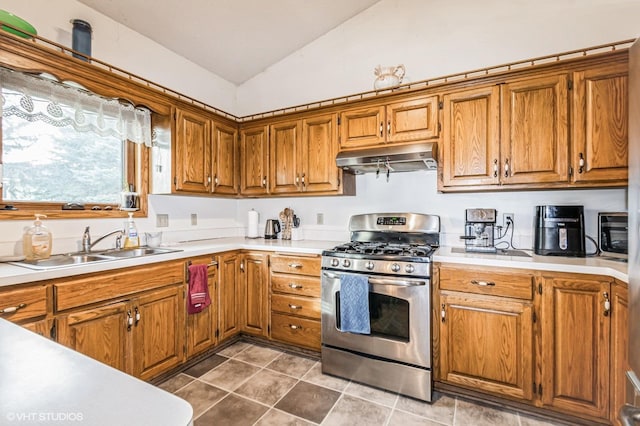 kitchen featuring under cabinet range hood, brown cabinetry, appliances with stainless steel finishes, and vaulted ceiling