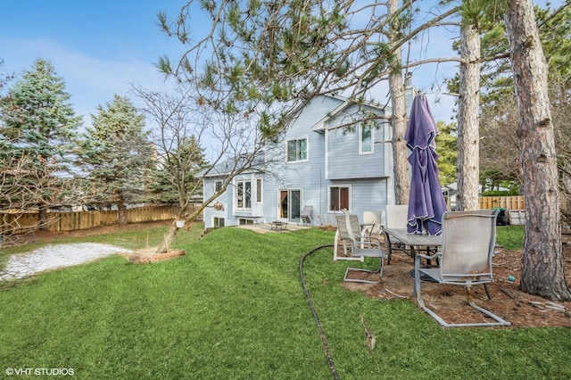 rear view of property featuring a lawn and fence