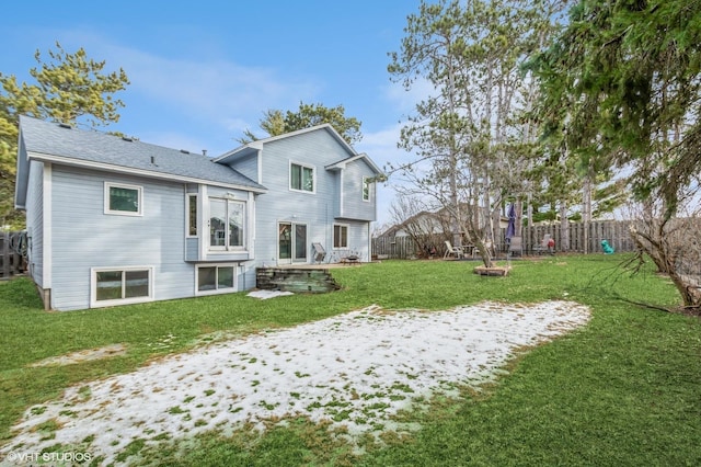 rear view of property with a yard, a shingled roof, and a fenced backyard