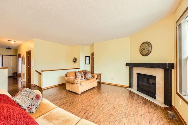 living room featuring a textured ceiling, wood finished floors, visible vents, and baseboards