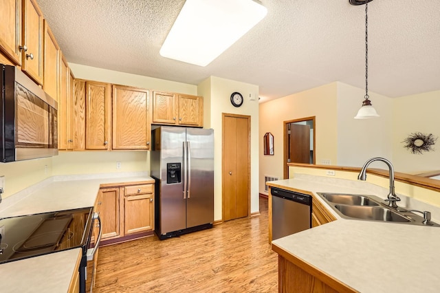 kitchen with visible vents, appliances with stainless steel finishes, light wood-style floors, hanging light fixtures, and a sink