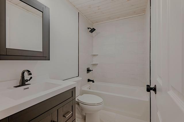 bathroom featuring wood ceiling, toilet, vanity, and bathtub / shower combination