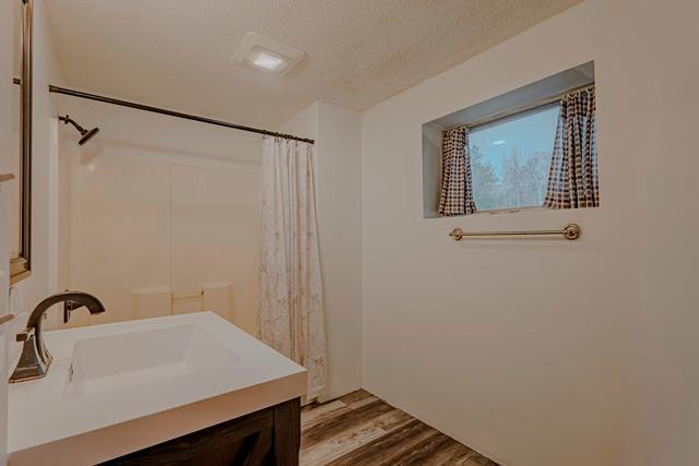 full bath featuring vanity, curtained shower, wood finished floors, and a textured ceiling