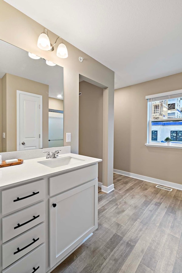 bathroom featuring wood finished floors, vanity, baseboards, and visible vents