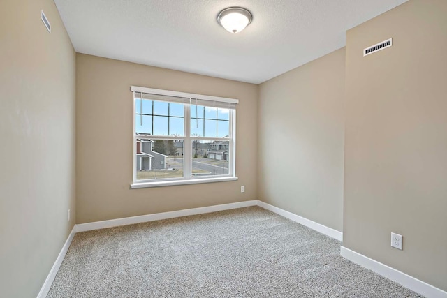 spare room featuring carpet floors, a textured ceiling, visible vents, and baseboards