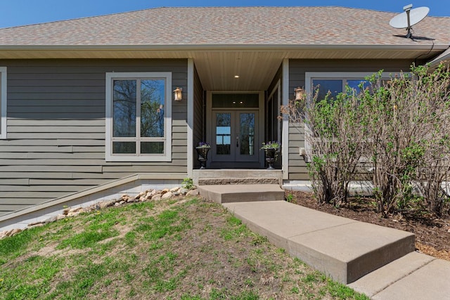 view of exterior entry with french doors and a shingled roof