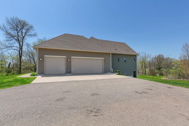 view of side of home featuring asphalt driveway and a garage
