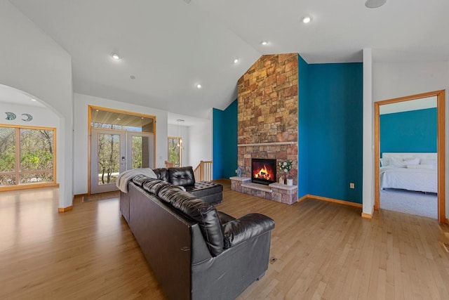 living area with plenty of natural light, light wood finished floors, a fireplace, high vaulted ceiling, and recessed lighting