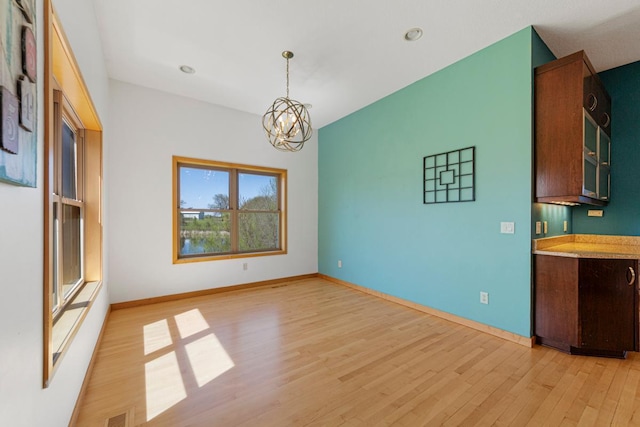 unfurnished dining area featuring light wood-style floors, a chandelier, baseboards, and recessed lighting
