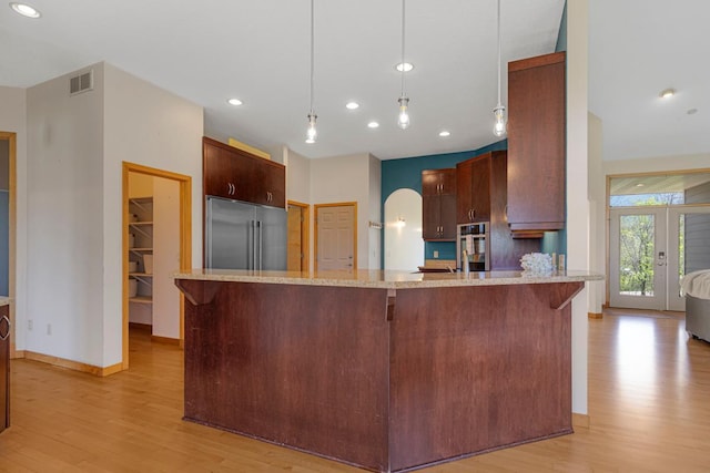kitchen featuring stainless steel appliances, light wood-style floors, a peninsula, light stone counters, and recessed lighting