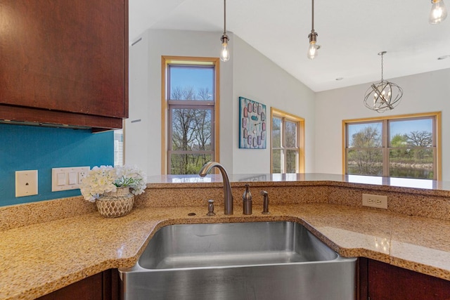 kitchen featuring a sink, light stone countertops, decorative light fixtures, and a chandelier