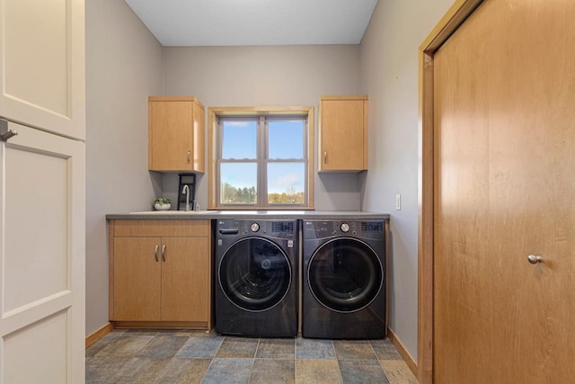 laundry room featuring washer and dryer, cabinet space, baseboards, and stone finish floors