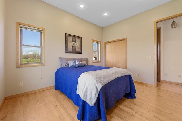 bedroom with light wood-type flooring, baseboards, recessed lighting, and a closet