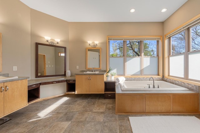 bathroom with a garden tub, vanity, and recessed lighting